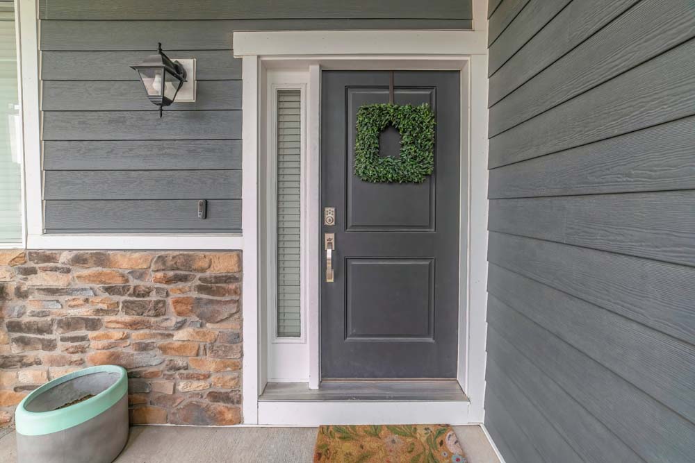 Entrance to a house with side light and gray front door decorated with wreath