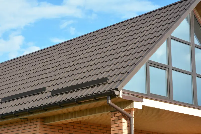 Building Modern House Construction with metal roof, rain gutter system and roof protection from snow board, snow bar (Snow guard). Roof Snow Guards: Building Materials & Supplies