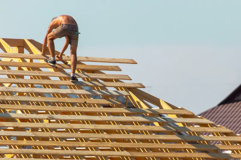 Workers are building the roof of the house from wood.